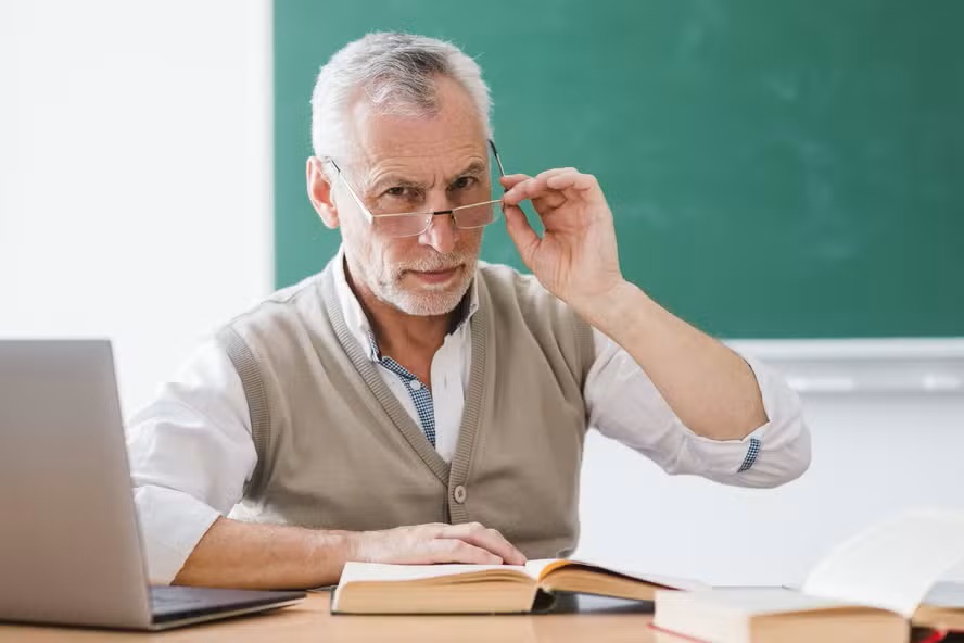 senior-professor-correcting-glasses-looking-camera-classroom.jpg